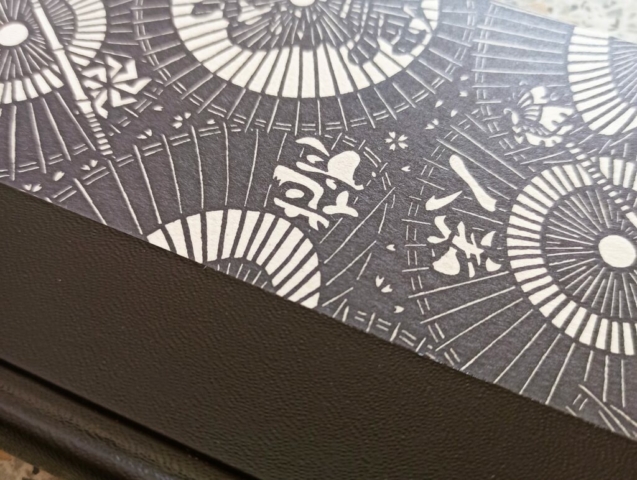 détail de couvrure, reliure Bradel demi-toile noire et papier à motif japonais