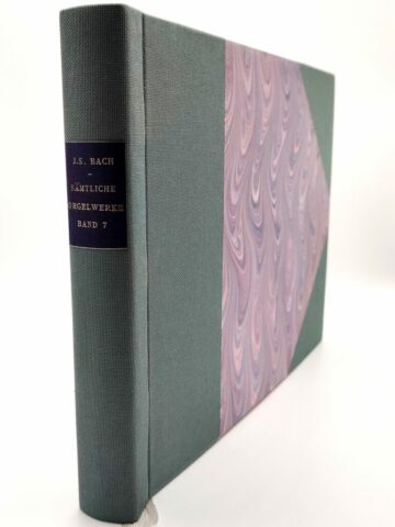 Reliure à la Bradel vue de biais, dorure sur le dos et couverture en papier marbré violet et toile verte